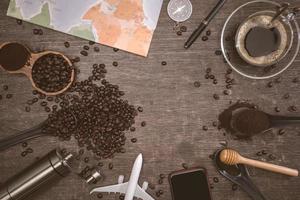 bruna kaffebönor och en kopp varmt kaffe placerade på ett träbord. koncept resor med karta. dags att koppla av med en kopp gott kaffe. ovanifrån kopiera utrymme för din text. foto