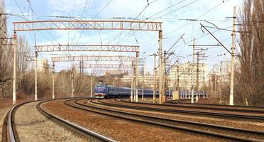 persontågvagnar av tåget åker på järnvägsspåren i bakgrunden av stadsbilden foto