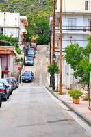 den öde gamla smala gatan i Loutraki i Grekland, den spruckna ytan på vägbanan, reser sig uppför. foto