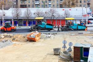 Kiev, Ukraina, 28.03.2020. stora asfaltläggare och en vägvibrerande vält går efter varandra vid bygget av en ny trafikplats. foto