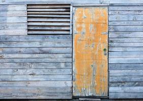 gammal väderbiten trälada med en gul gammal dörr