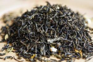 kinesiskt torrt te på träbakgrund, jasminte torkat för bryggte, lövsvart te foto