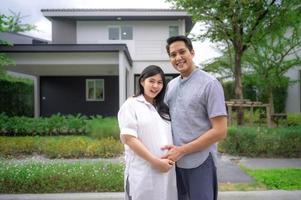 asiatiskt par som står utanför sitt nya hus
