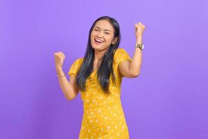 porträtt av upphetsad ung asiatisk kvinna som firar framgång på lila bakgrund foto