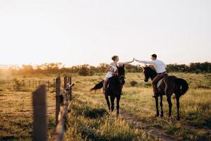 flicka i vit solklänning och en kille i vit skjorta på promenad med bruna hästar foto