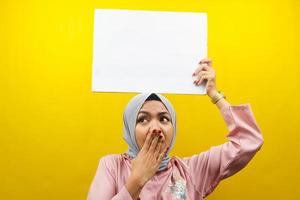 ganska ung muslimsk kvinna chockad, förvånad, wow, hand som håller en tom banderoll, plakat, vit tavla, tom skylttavla, vit reklamtavla, presentera något i kopieringsutrymmet, marknadsföring foto