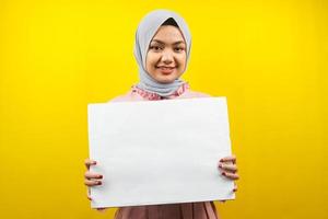 ganska ung muslimsk kvinna gladlynt hållande tom tom banderoll, plakat, vit tavla, tom skylttavla, vit reklamtavla, presentera något i kopia utrymme, marknadsföring foto