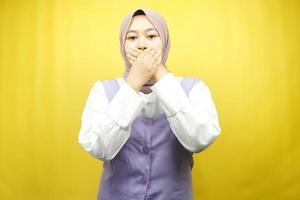 vacker ung asiatisk muslimsk kvinna chockad, förvånad, misstroende, får chockerande information, med händer som täcker munnen isolerad på gul bakgrund foto