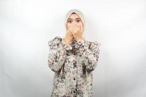 vacker ung asiatisk muslimsk kvinna chockad, förvånad, misstroende, får chockerande information, med händer som täcker munnen isolerad på vit bakgrund
