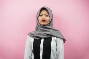 vacker asiatisk ung muslimsk kvinna som tutar och tittar på kameran isolerad på rosa bakgrund foto