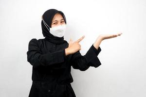 muslimsk kvinna som ler självsäkert med händer som pekar på tomt utrymme, presenterar något, presenterar produkt, isolerad på vit bakgrund foto