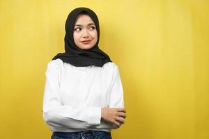 vacker ung asiatisk muslimsk kvinna som blåser, känner sig missnöjd, irriterad, olycklig, tänker, något är fel, vänder mot ett tomt utrymme isolerat på gul bakgrund foto