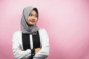 vacker ung asiatisk muslimsk kvinna som blåser, känner sig missnöjd, irriterad, olycklig, tänker, något är fel, vänder mot ett tomt utrymme isolerat på rosa bakgrund foto