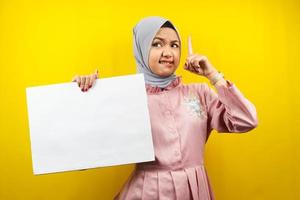 ganska ung muslimsk kvinna får idé, hand som håller en tom banderoll, plakat, vit tavla, tom skylttavla, vit reklamtavla, presenterar något i kopieringsutrymmet, marknadsföring foto