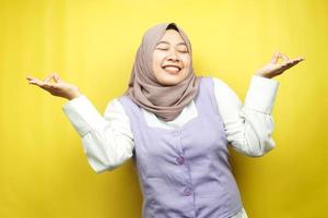 vacker ung muslimsk kvinna med händer som mediterar tecken, ler bekväm och glad, isolerad på gul bakgrund foto