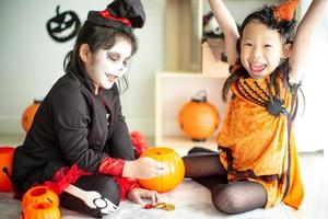porträtt av två glada systrar i halloween-kostymen som delar godiset och chokladen från trick or treat
