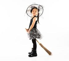 porträtt asiatisk liten flicka klädd i söt häxa för halloween kostym med kvast foto