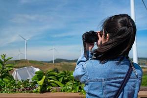 porträtt av kvinna som tar bilder av vindkraftverk foto