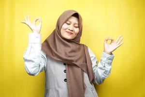 vacker ung muslimsk kvinna med händer som mediterar tecken, ler bekväm och glad, isolerad på gul bakgrund foto