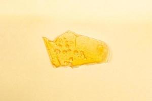 bit bärnstensfärgad cannabisvax på gul bakgrund foto