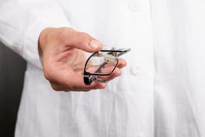 optiker med glasögon i hand i vit rock