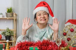 asiatisk kvinna fira nyår och julfest med surfplatta videosamtal vänner hemma foto