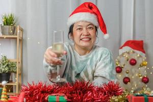 asiatisk kvinna som rostar champagne firar nyår och julfest videosamtal vänner hemma foto