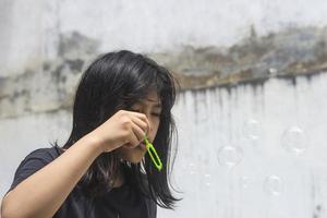 en tjej som håller i en bubbelmaskin och blåser ut dem. foto