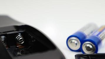 svart fjärrkontroll med blå aaa-batterier på en vit bakgrund. batteribyte, reservdelar. batteritomt fack i fjärrkontrollen närbild. foto