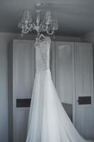 brudens brudklänning hänger på ljuskronan. bröllop. selektiv fokusering. filmkorn. foto