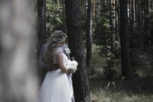 brudparet omfamnar i skogen på bröllopsdagen. bröllopsceremoni. selektiv fokusering. filmkorn. foto