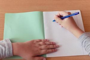 hand av en tonårsflicka skriver med en kulspetspenna i en terad under en lektion i skolan foto