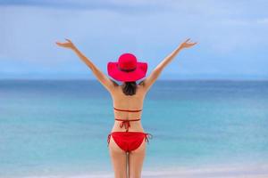 ung asiatisk kvinna i bikini med hatt stående på stranden sommarsemester phuket thailand foto
