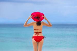 ung asiatisk kvinna i bikini med hatt stående på stranden sommarsemester phuket thailand foto