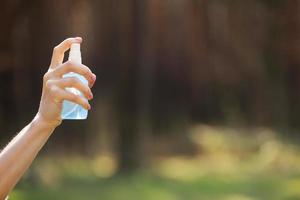 kvinna hand som håller alkoholspray eller anti-bakterier spray utomhus för att förhindra spridning av bakterier, bakterier och virus, karantäntid, fokusera på nära händer. coronavirus. kopieringsutrymme. selektiv fokusering foto