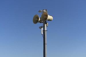 en stolpe med en högtalare på en blå himmel bakgrund foto