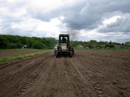 plöjd åker med traktor i brun jord på öppen natur foto