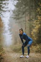 ung kvinna ta en paus under utomhusträning på skogsstigen på hösten