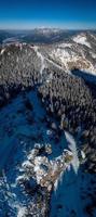 Flygfoto över berget med snötäckta tallar i bayern vid garmisch partenkirchen foto