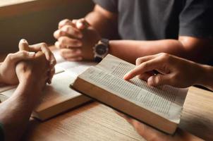 ung man som läser bibeln med vänner som ber till gud gå med i cellgruppen i kyrkan. en liten grupp kristna eller koncept i en kyrka vid en kyrka. foto