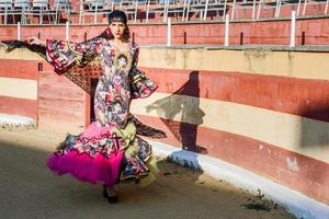 kvinna, modell av mode, klädd i en klänning i en tjurfäktningsarena foto