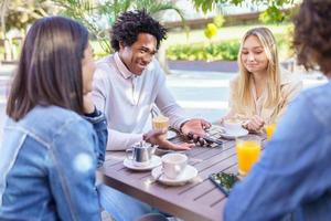 multietnisk grupp studenter som tar en drink på terrassen till en gatubar. foto