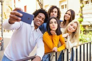 multietnisk grupp vänner som tar en selfie utomhus med en smartphone. foto