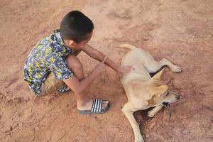 en asiatisk pojke som leker utomhus med sin hund foto