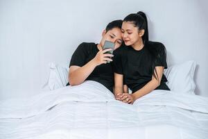 två kärleksfulla kvinnor som sover och spelar smartphones. foto