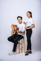 två unga kvinnor satt på en stol och spelade gitarr. foto