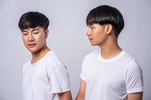 två förälskade män klädda i vita t-shirts tittade på varandras ansikten. foto