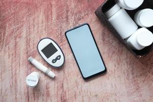 smart telefon och diabetiker mätverktyg och piller på bordet foto