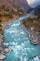 naturflod som rinner från berg längs Puh Hill vandringsväg med naturskogsmiljö i nepal.