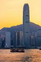 Hongkong turistbåt för turistservice i Victorias hamn med stadsvy i bakgrunden vid solnedgångsvy från Kowloon-sidan i Hongkong